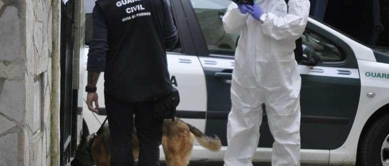 El perro busca, con su guía, rastros a la entrada de la casa de Navia.