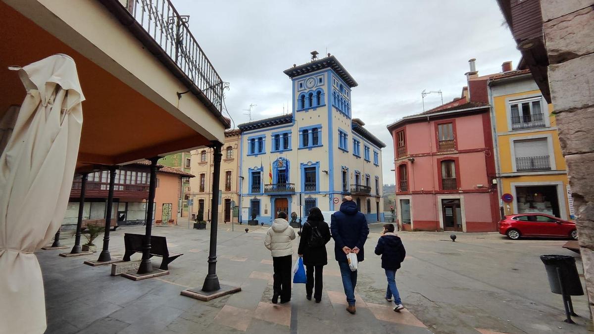 Una familia, en la plaza del Ayuntamiento de Grado, con el edificio al fondo de la imagen.