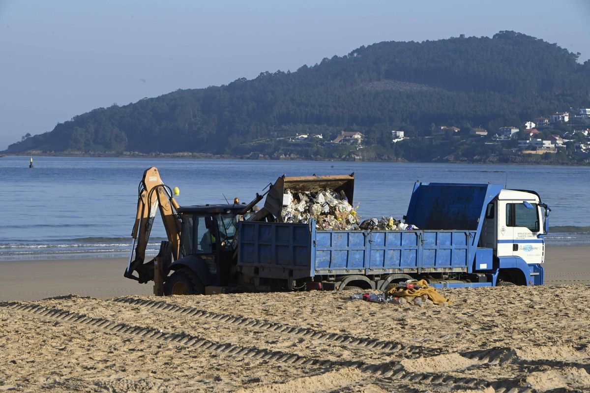 Una excavadora vuelca la basura en un camión en Praia América esta mañana.