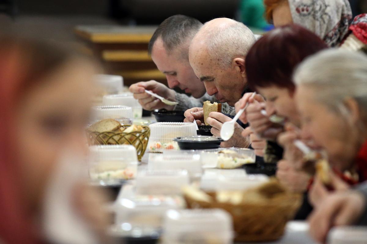 Refugiados rezan antes de almorzar en un centro de refugiados dentro de la Iglesia Bautista Central en Dnipro, Ucrania