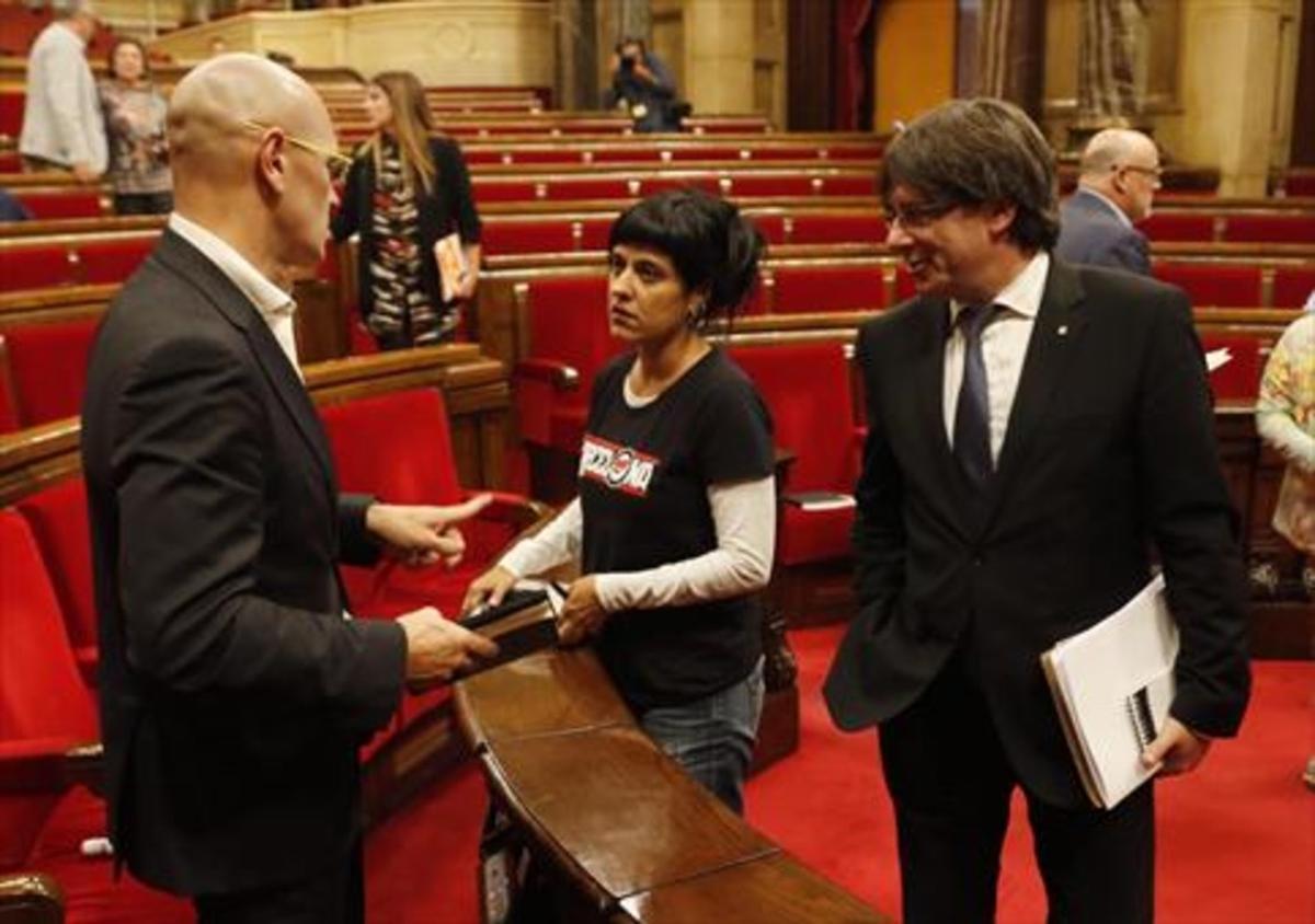 Carles Puigdemont observa a la diputada de la CUP Anna Gabriel y al 'conseller' Romeva, en el Parlament.