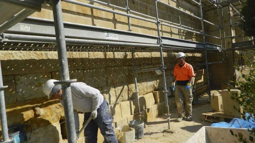 Dos operarios trabajan en la restauración de la iglesia de Casaseca de las Chanas.