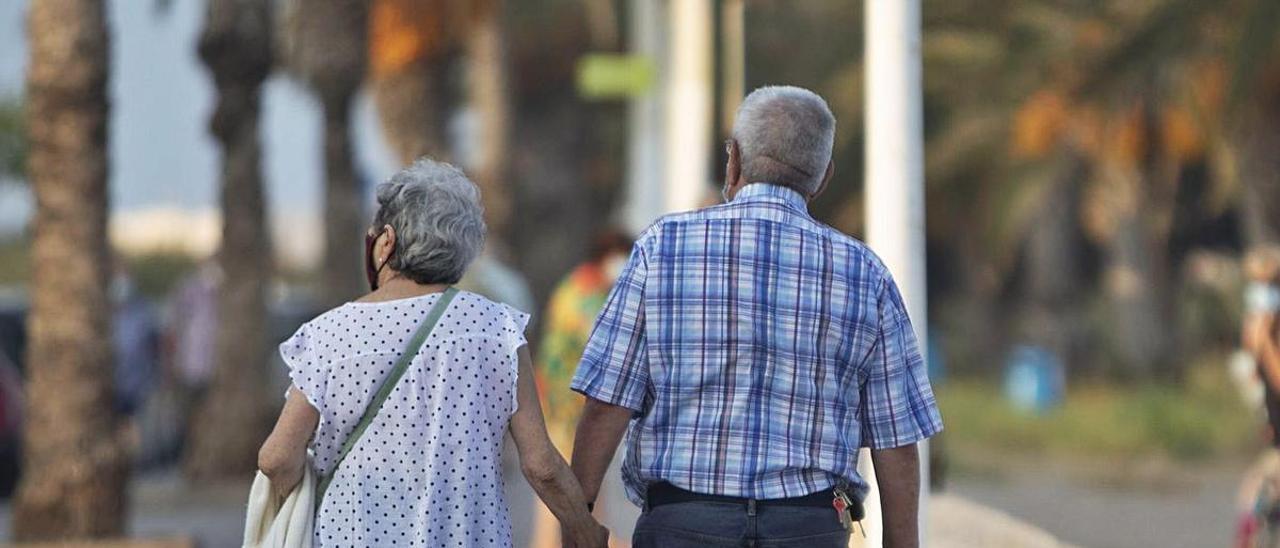 Una pareja de jubilados pasea cogida de la mano. | DANIEL TORTAJADA