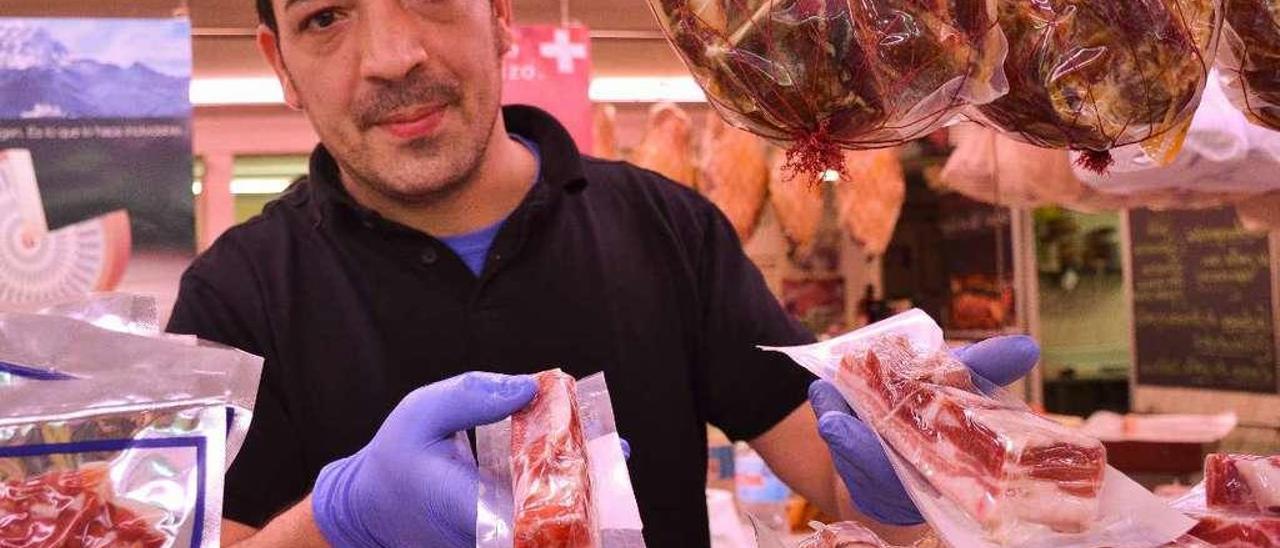 Ignacio García García, carnicero de Riodi, en Oviedo, muestra un trozo de panceta y otro de tocino en la carnicería del establecimiento.