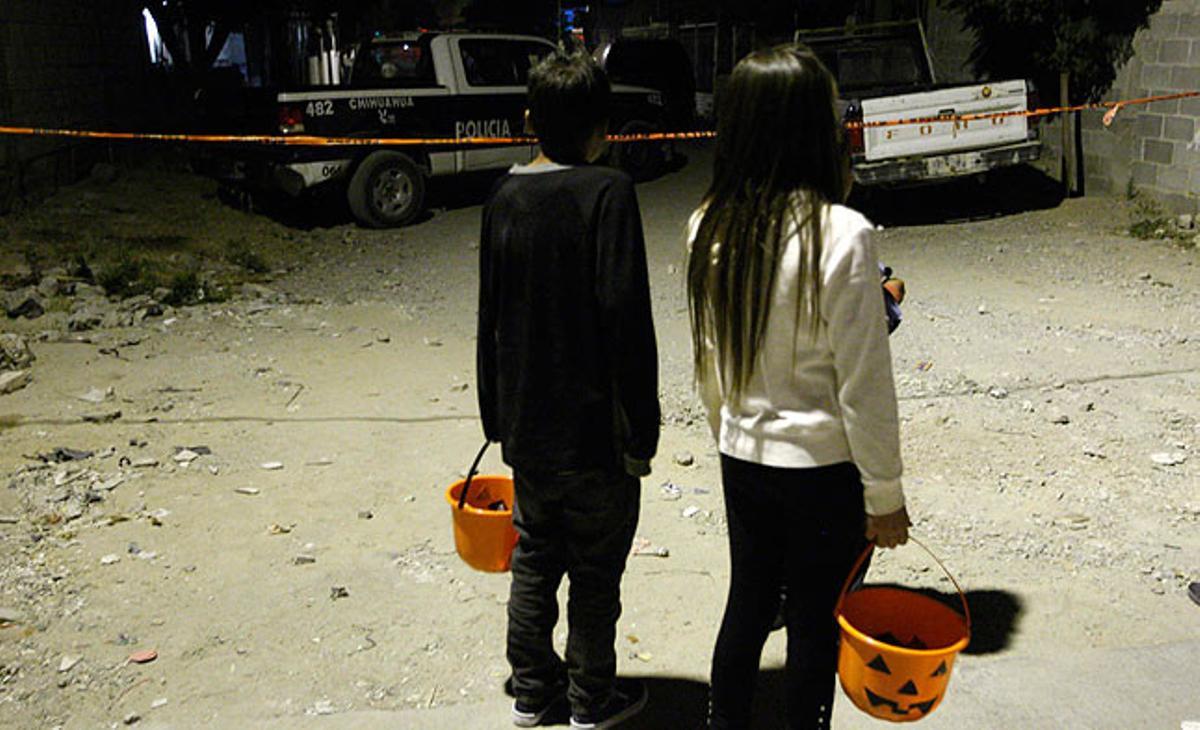 Dos nens vestits per celebrar Halloween observen l’escenari d’un crim a Ciudad Juárez, Mèxic.