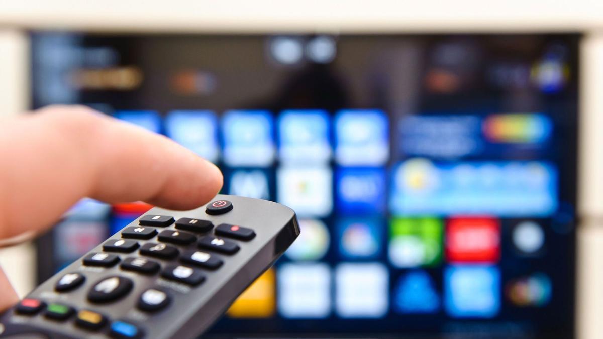 Una persona frente a un televisor con un mando a distancia.