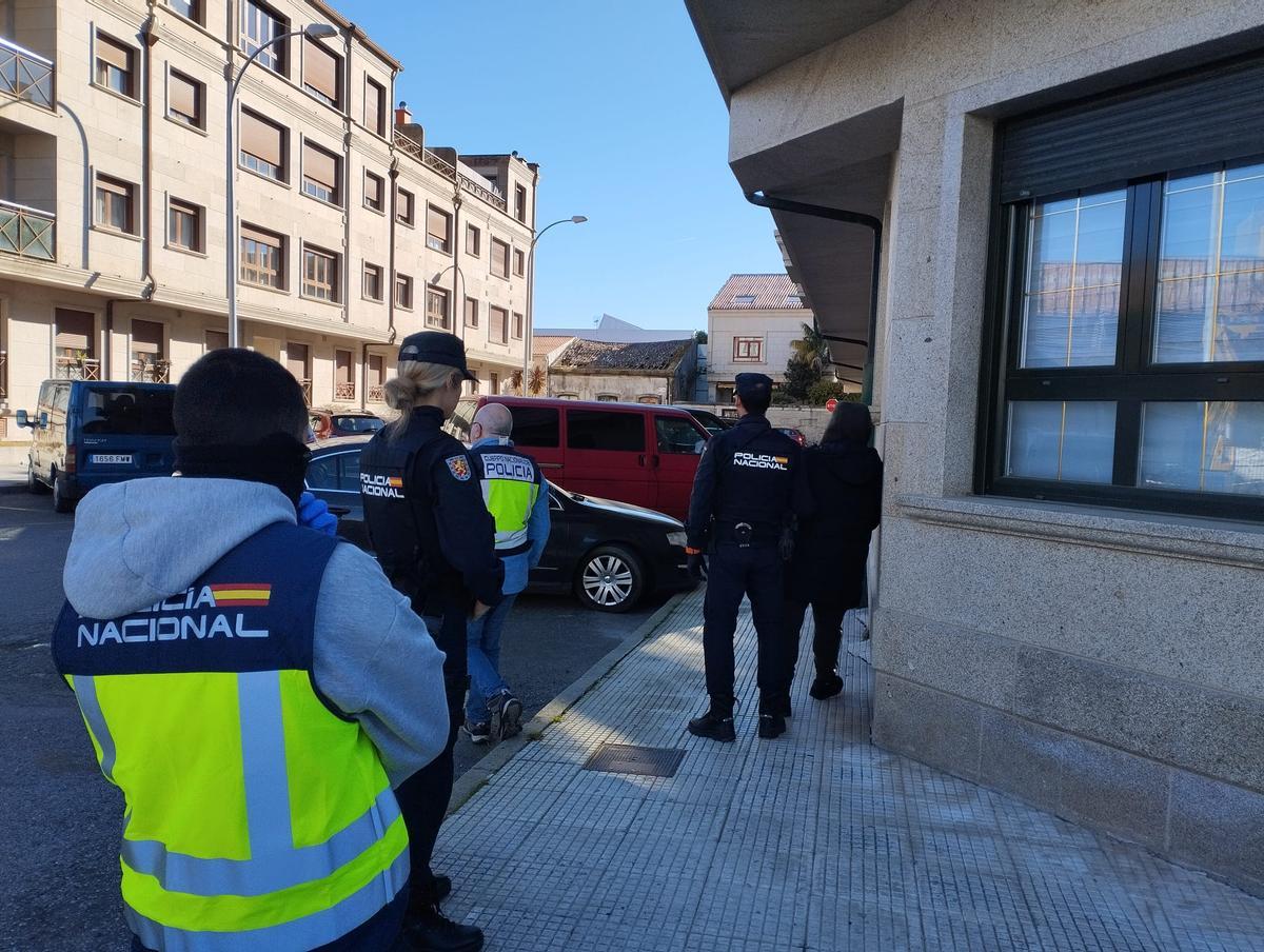 El detenido en Vilagarcía, de espaldas a la derecha de la imagen, custodiado por un agente.