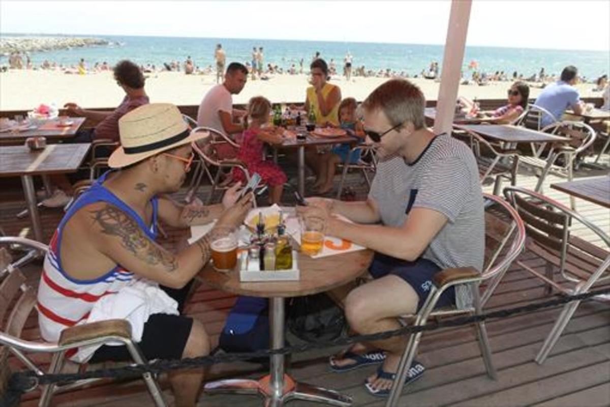 CONECTADOS Turistas usando sus móviles en un restaurante de Barcelona.