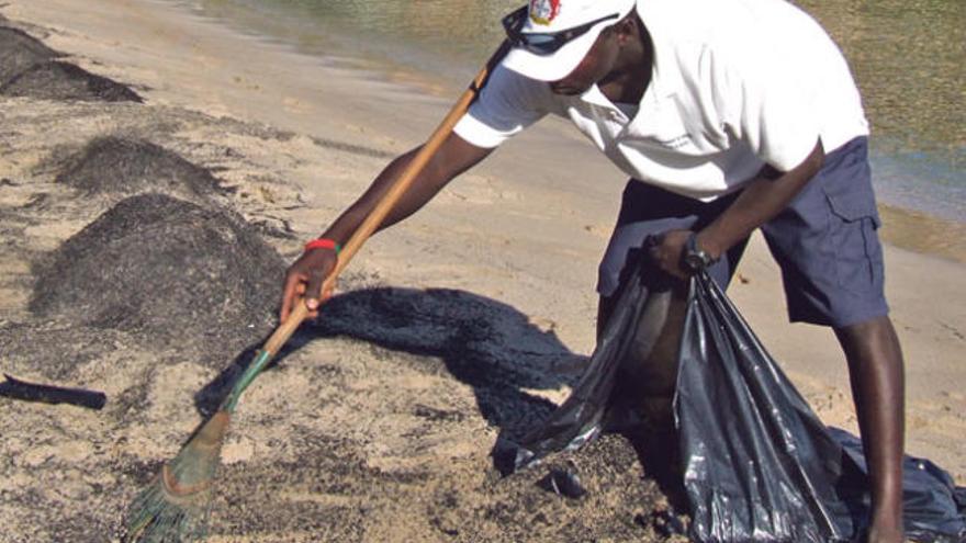 Un operario retira las cenizas de la playa.