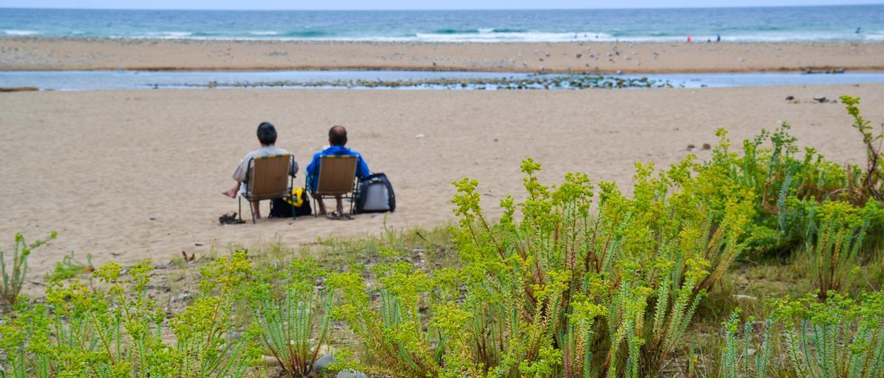 Dos usuarios de la playa, contemplando el mar.