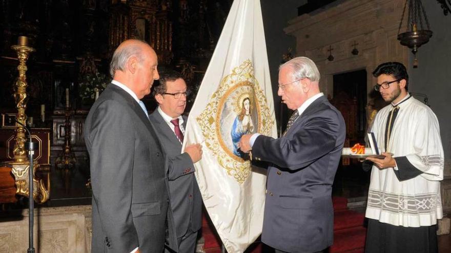 Ángel Bueres poniendo la medalla en la bandera de la Inmaculada, sujetada por Iñaqui Basterra, fiscal de la Cofradía, que está acompañado por Rogelio Díaz-Agero, del Cuerpo de la Nobleza.