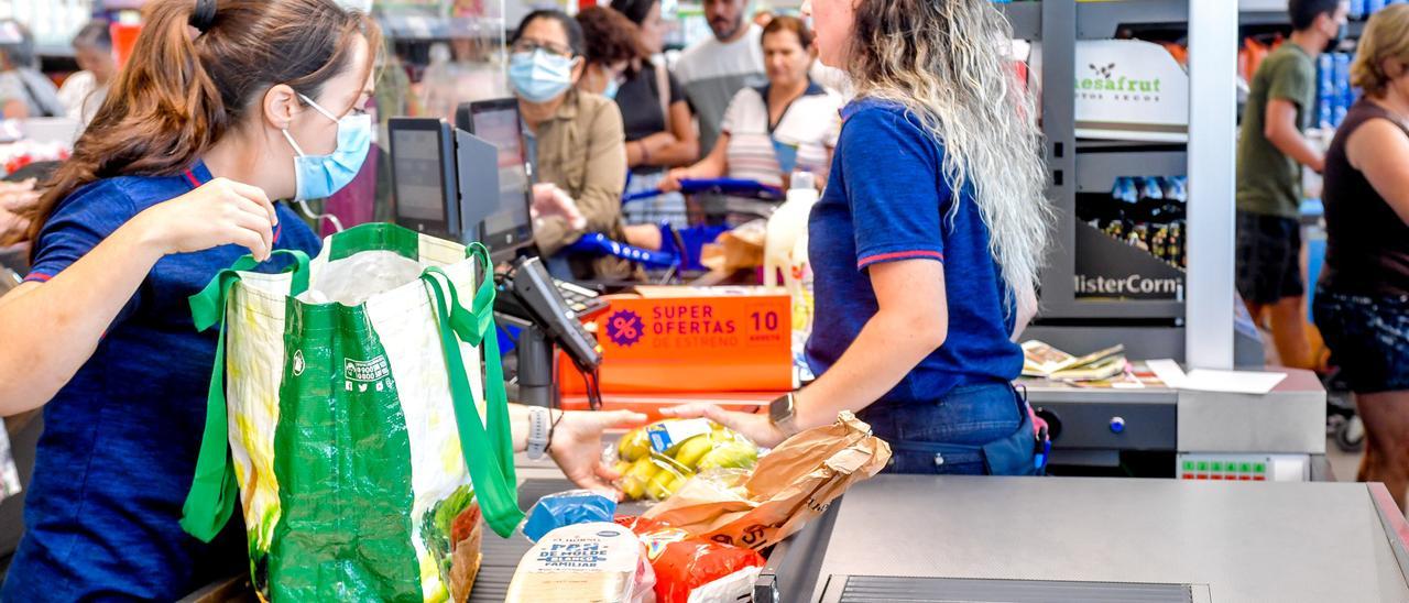 Una cajera pasa la compra de una clienta en un supermercado del Archipiélago.