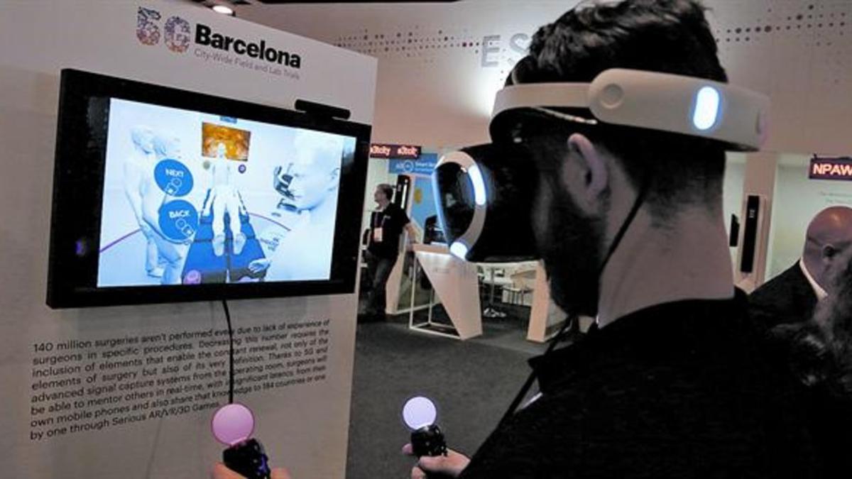 Un visitante del MWC simula participar en una operación a distancia con ayuda de la tecnología 5G, el miércoles en el MWC.