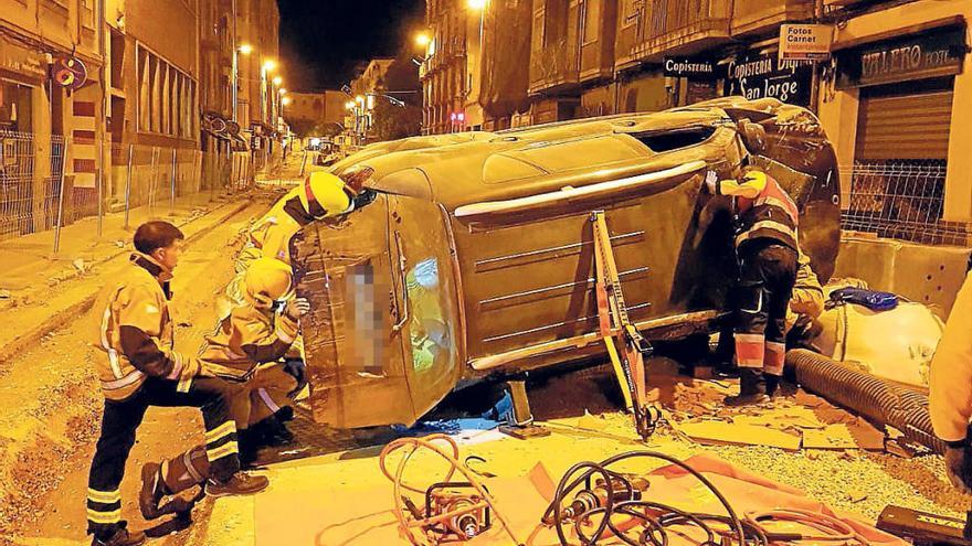 Los bomberos en el momento de rescatar al conductor del interior del vehículo volcado.