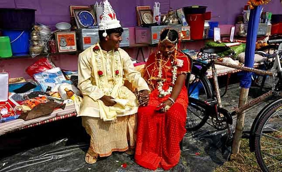 Una parella de nuvis està asseguda al costat de les seves pertinences, que van ser donades a una organització no governamental, durant la celebració del casament en massa al poblet de Bahirkhand, al nord de Calcuta (Índia).