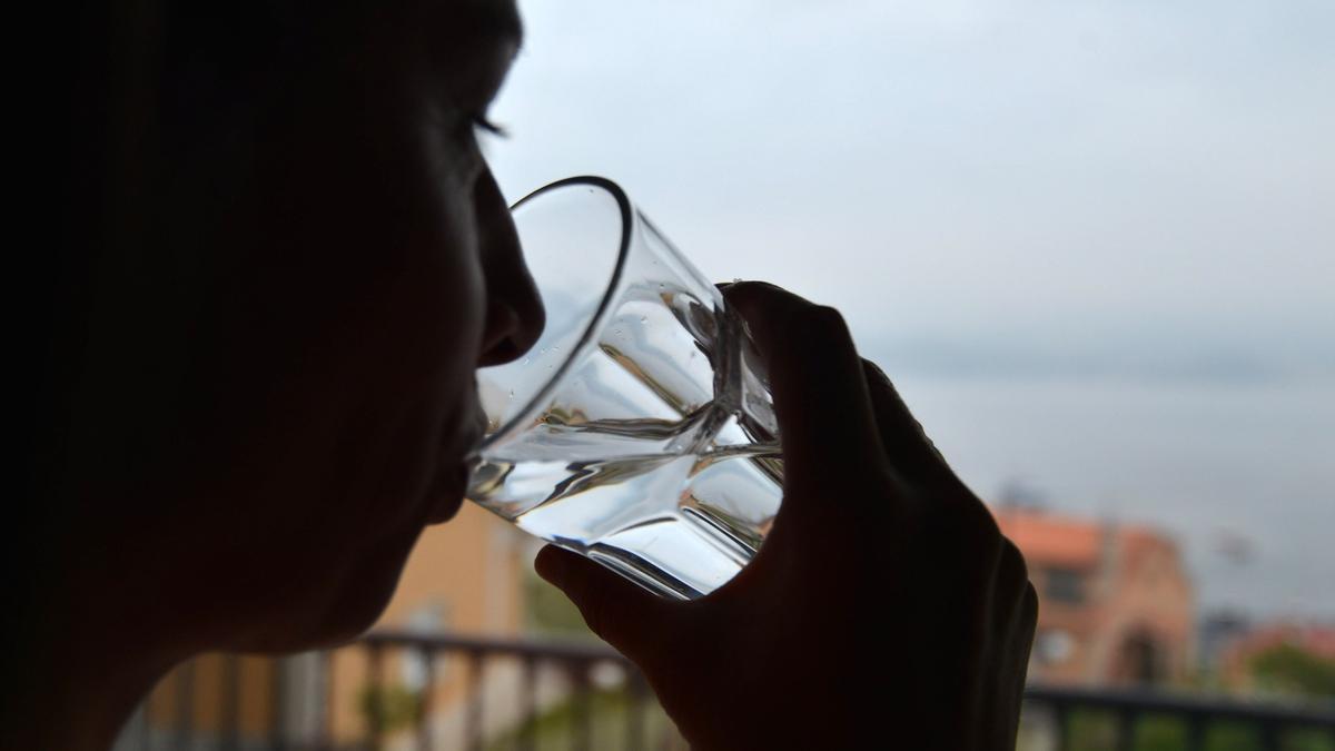 UNA MUJER BEBE UN VASO DE AGUA.