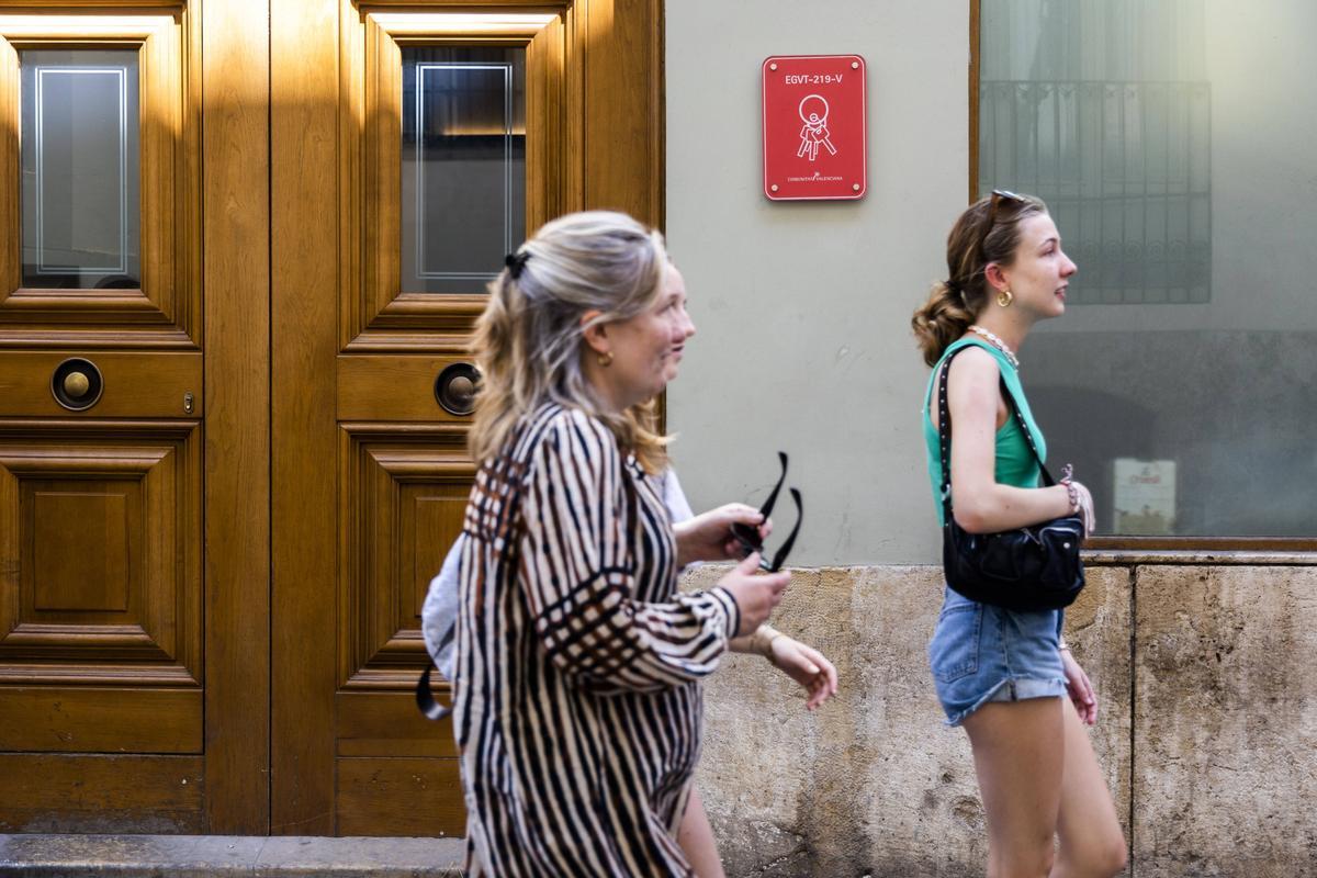 Tres turistas pasan ante un edificio de apartamentos turísticos en el centro de la capital del Túria.