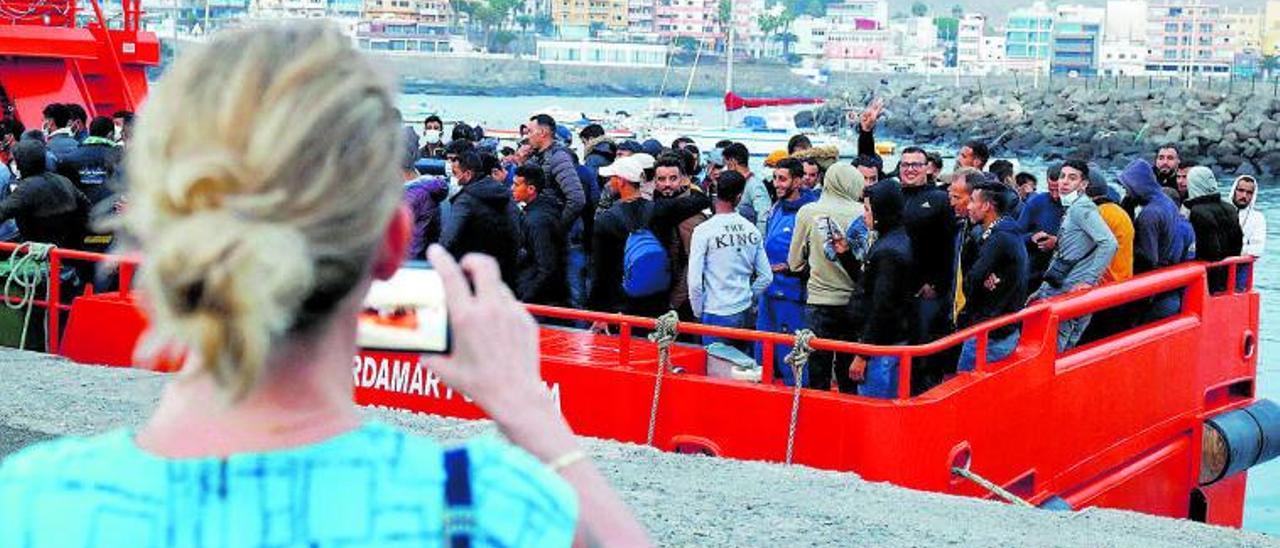 Una turista fotografía el desembarco de un grupo de migrantes en el puerto de Arguineguín, en Gran Canaria.