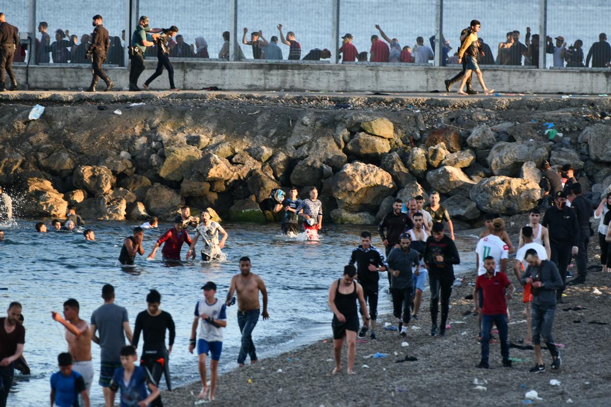 Personas migrantes caminan por la playa del Tarajal, en Ceuta, el pasado 17 de mayo de 2021. 