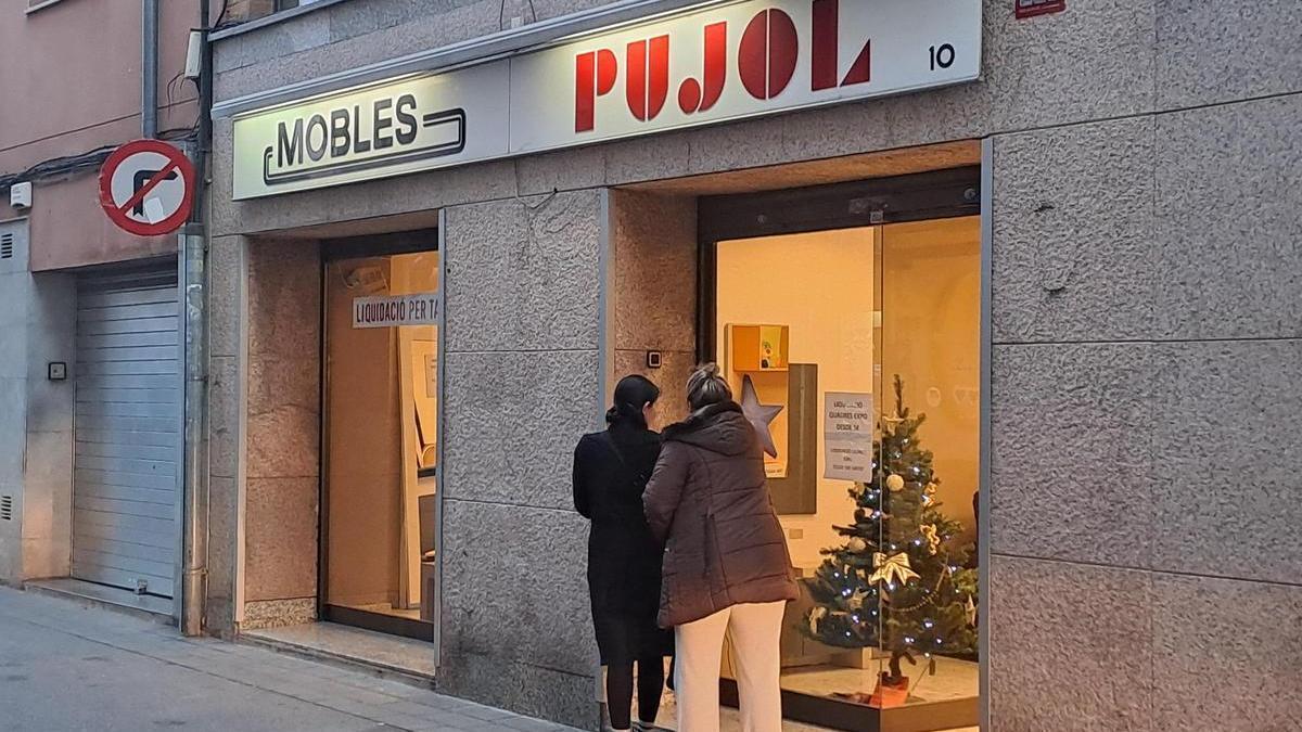 Dues dones observen els articles en liquidació de Mobles Pujol