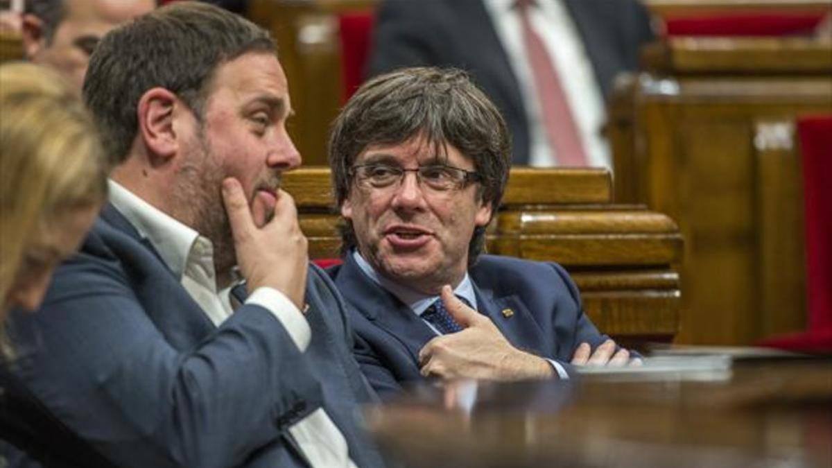 El jefe del Govern, Carles Puigdemont, con el vicepresidente, Oriol Junqueras, ayer, en el Parlament.