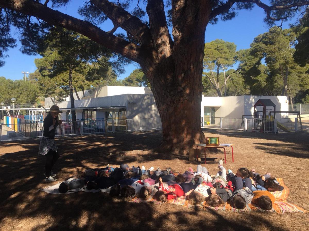 Alumnes d'Infantil en una activitat del projecte Lecto-Natura, gaudint de la lectura sota l'ombra del Piverot