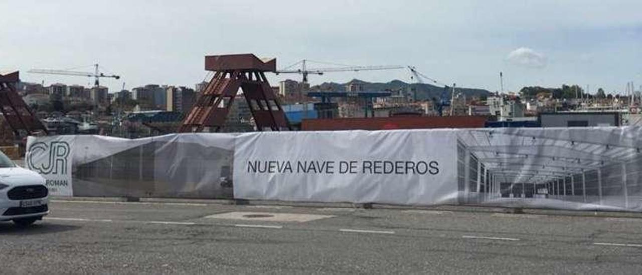 Parte de los 3.000 m2 vallados para la nave de rederos en el muelle de Reparaciones y una lona con la infografía del proyecto. // FdV