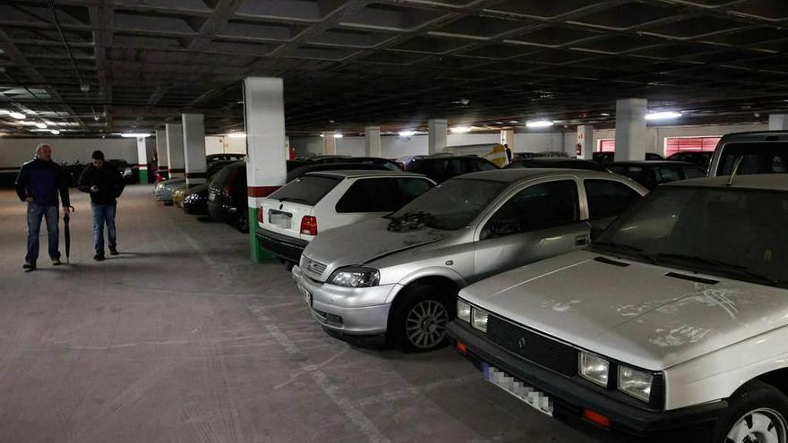 Dos interesados en la puja examinando ayer los coches en las dependencias de la grúa municipal.