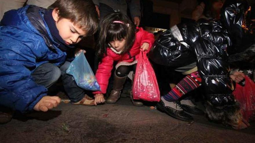 Niños recogen caramelos del suelo durante la última cabalgata de Reyes.