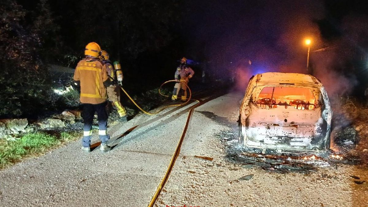 El cotxe a la pujada dels Polvorins totalment cremat i els Bombers actuant.