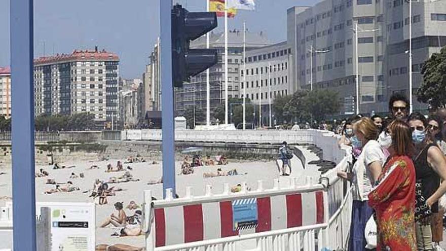 Bañistas con mascarillas hacen cola para acceder a la playa del Orzán.