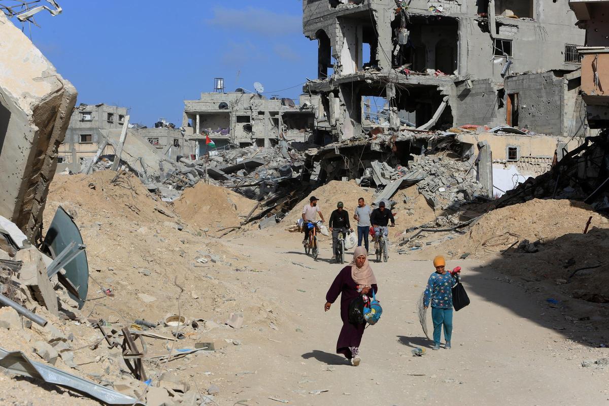 Los palestinos inspeccionan las casas y carreteras en gran parte destruidas después de que el ejército israelí se retirara de la ciudad de Abasan.