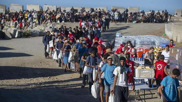 Membres de la Creu Roja reparteixen menjar als immigrants en una platja de Ceuta.