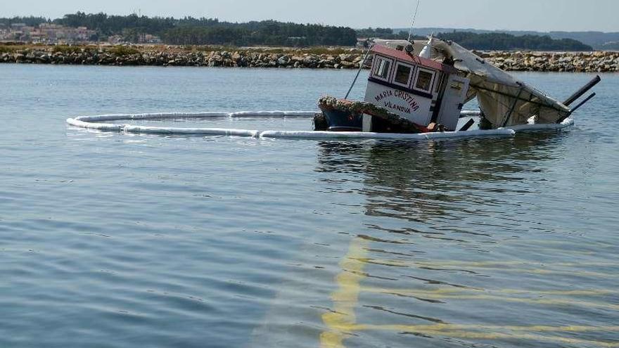 El barco, rodeado de barreras anticontaminación en el muelle de Vilanova. // Noé Parga