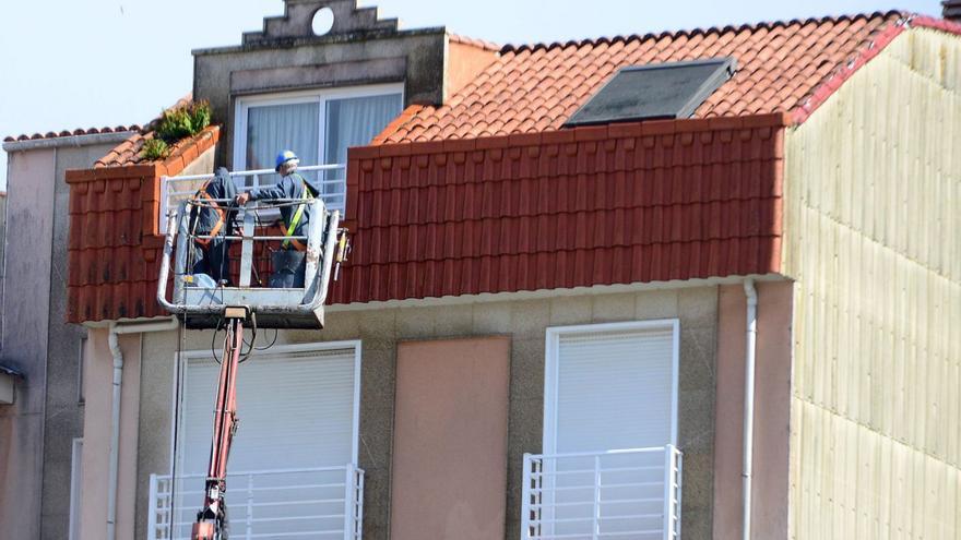 Operarios de la construcción, trabajando en la fachada de un edificio de la comarca.