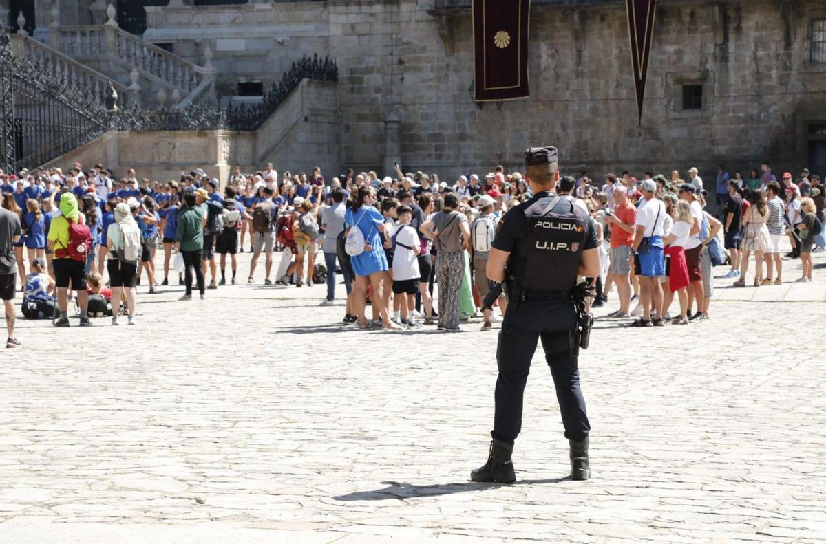 Un agente policial vigilando el flujo de peregrinos y turistas en la plaza del Obradoiro / antonio hernández