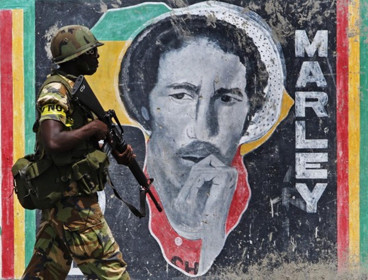 Un soldat passa davant la imatge del músic de reggae i pacifista Bob Marley al barri de Tivoli Gardens, a la capital jamaicana. La setmana passada, el govern seguia buscant el suposat baró de la droga Christopher Dudus Coke. Ara se suposa que el narcotraficant ha fugit del país. Un soldat passa davant la imatge del músic de reggae i pacifista Bob Marley al barri de Tivoli Gardens, a la capital jamaicana. La setmana passada, el govern seguia buscant el suposat baró de la droga Christopher Dudus Coke. Ara se suposa que el narcotraficant ha fugit del país.