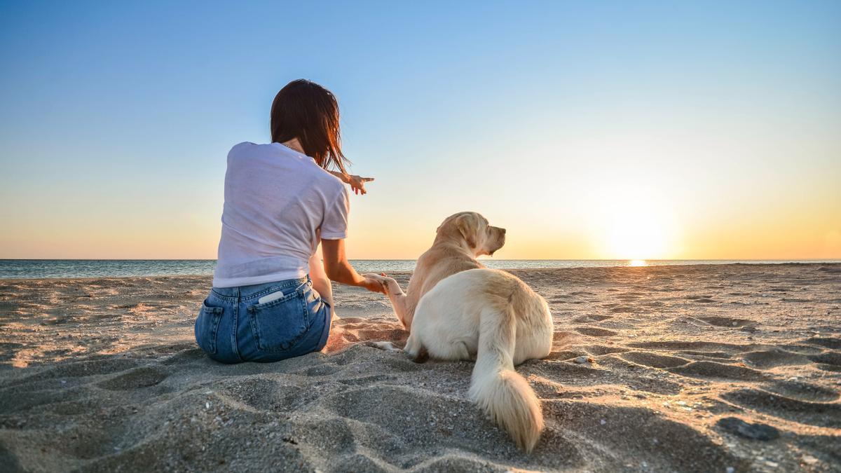 Una mujer con su perro en la playa.