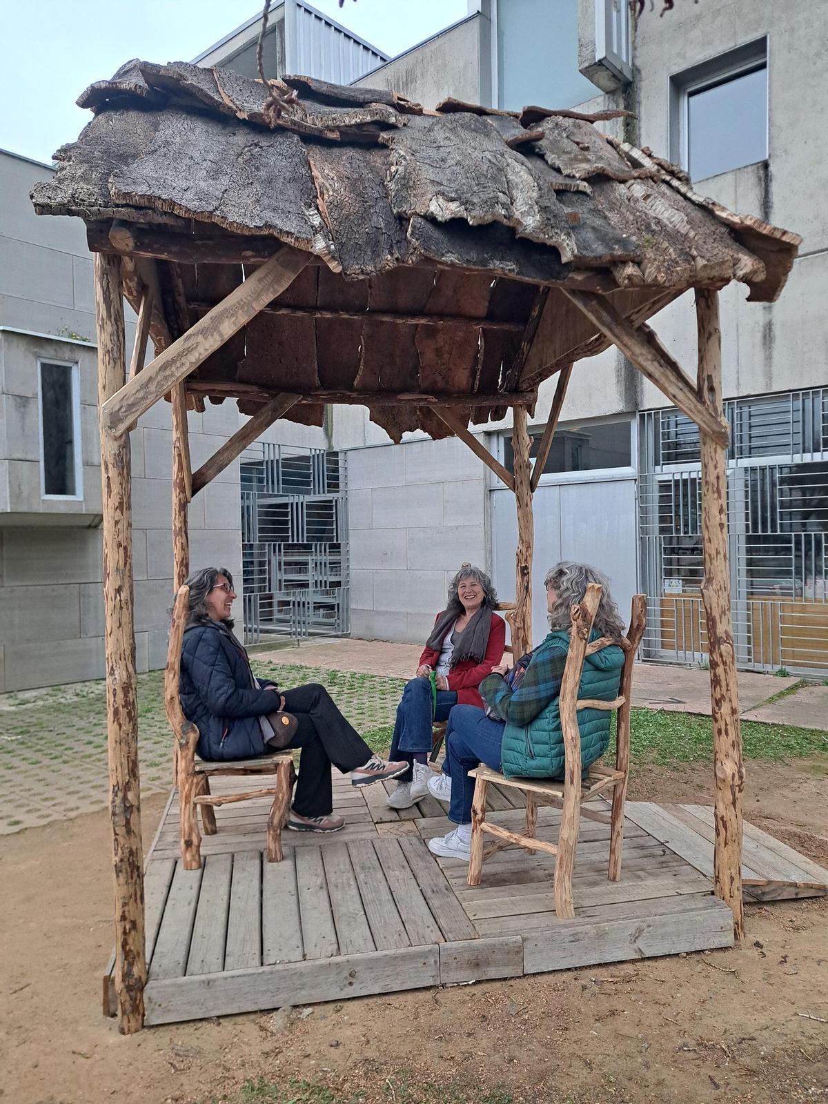 Tres veïnes s'asseuen a la instal·lació "Tinc tres cadires" de l'artista Jofre Sebastian a la plaça de l'Om de Pont Major, a Girona.