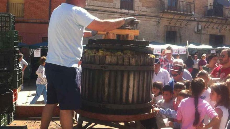 Un prensador estruja la uva para conseguir el mosto ante la mirada de niños y vecinos de Morales .
