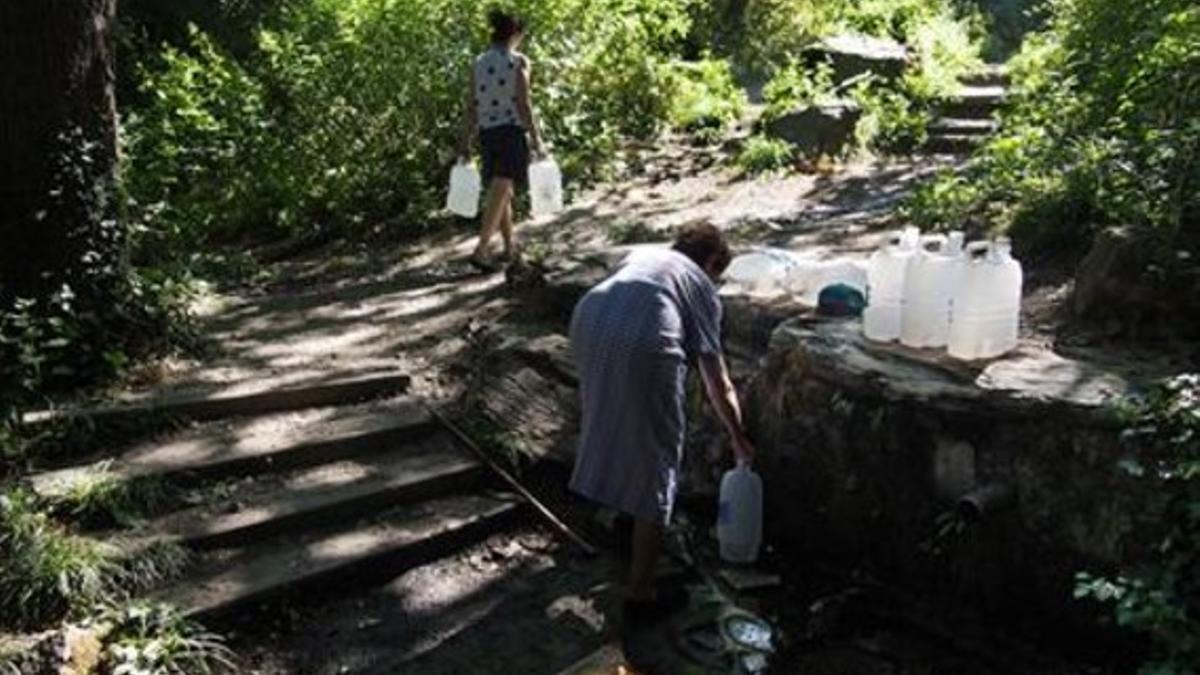 Un grupo de personas llena sus garrafas en la fuente d'en Vinyes.