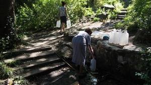 Un grupo de personas llena sus garrafas en la fuente d’en Vinyes.