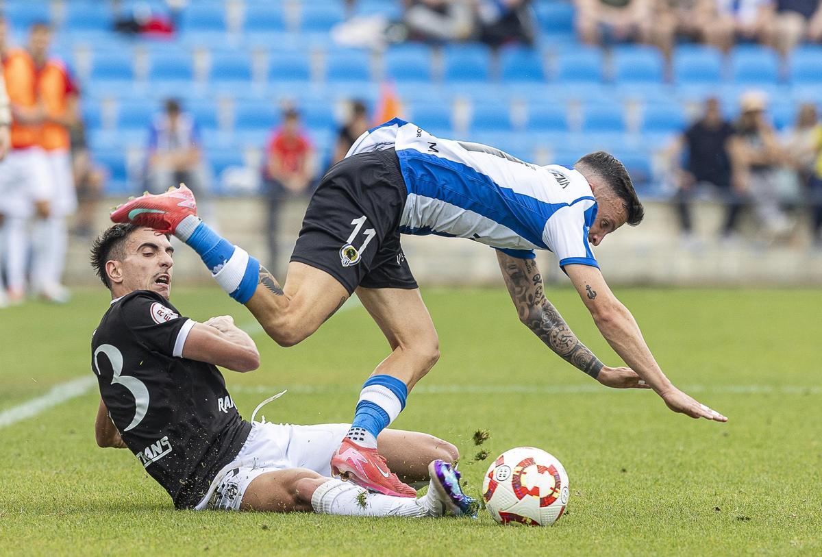 El jugador del Mérida Busi se lanza al suelo para frenar el avance de Javi Moreno.