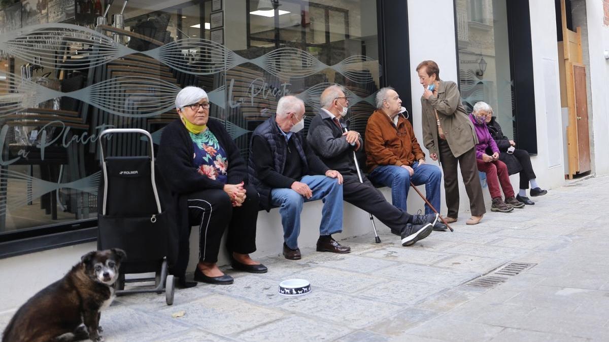 Amb les mesures restrictives per la Covid-19, l&#039;única opció que els queda a aquests veïns és comprar l&#039;esmorzar per prendre-se&#039;l a la porta del bar. Són molt curosos amb les mesures de seguretat, si bé per a la foto es col·loquen bé i alguns d&#039;ells es baixen uns segons la mascareta per mostrar el rostre.