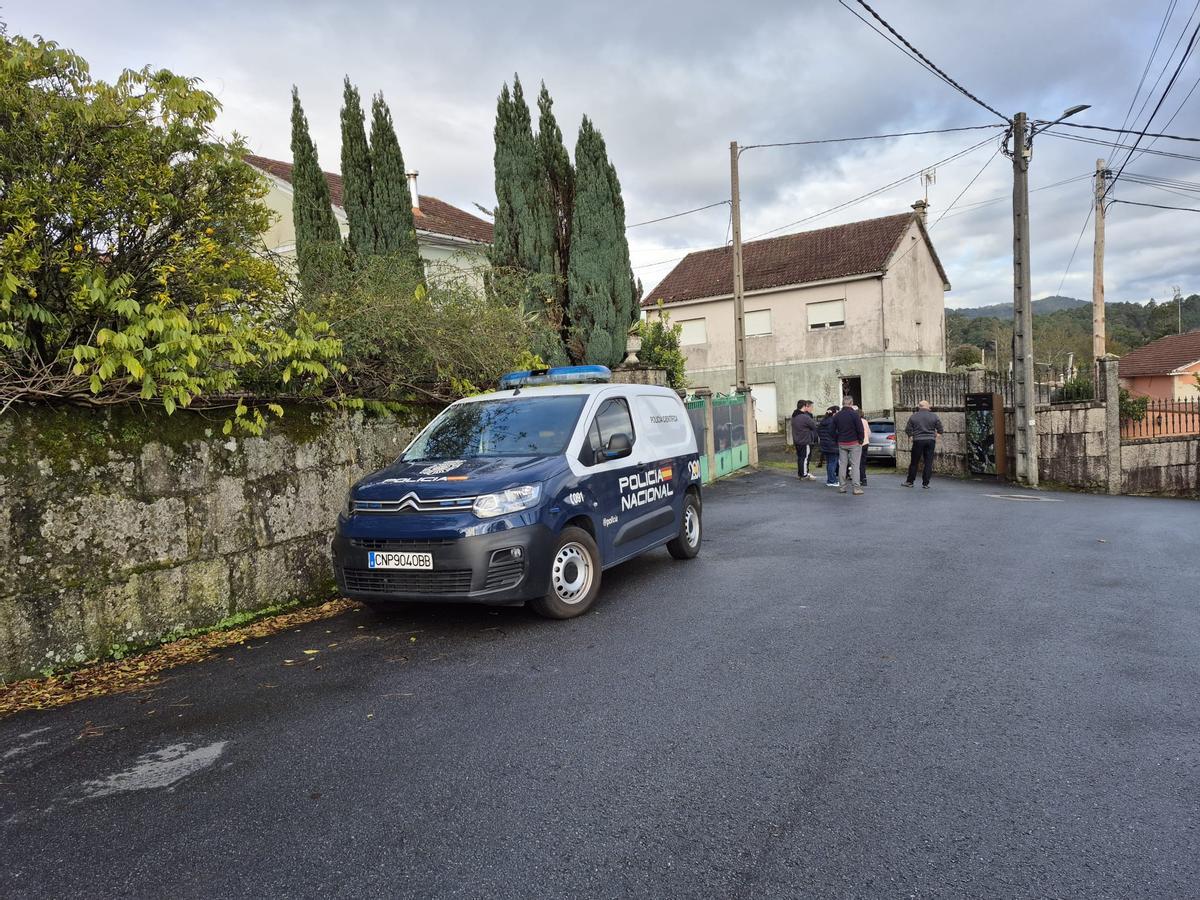 Un coche policial y vecinos ante la casa del hombre fallecido.