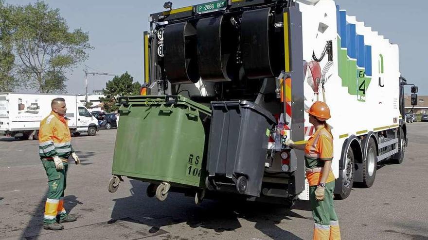 Dos operarios cargan el nuevo camión bicompartimentado de Emulsa con los contenedores de residuos vegetales (verde) y mezclados (negro).