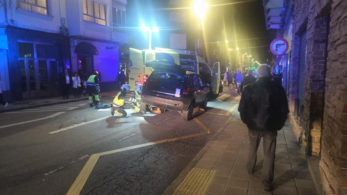 Bomberos rescatando a una mujer que quedó debajo de un coche tras ser atropellada en Mieres