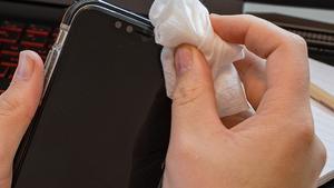 Una persona limpia los bordes de su teléfono móvil,
