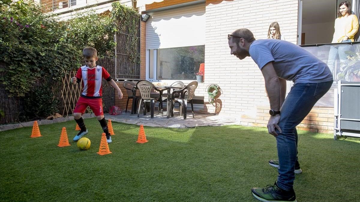 Víctor, jugador de la UD Viladecans, en el jardín de su casa entrenando con su padre.