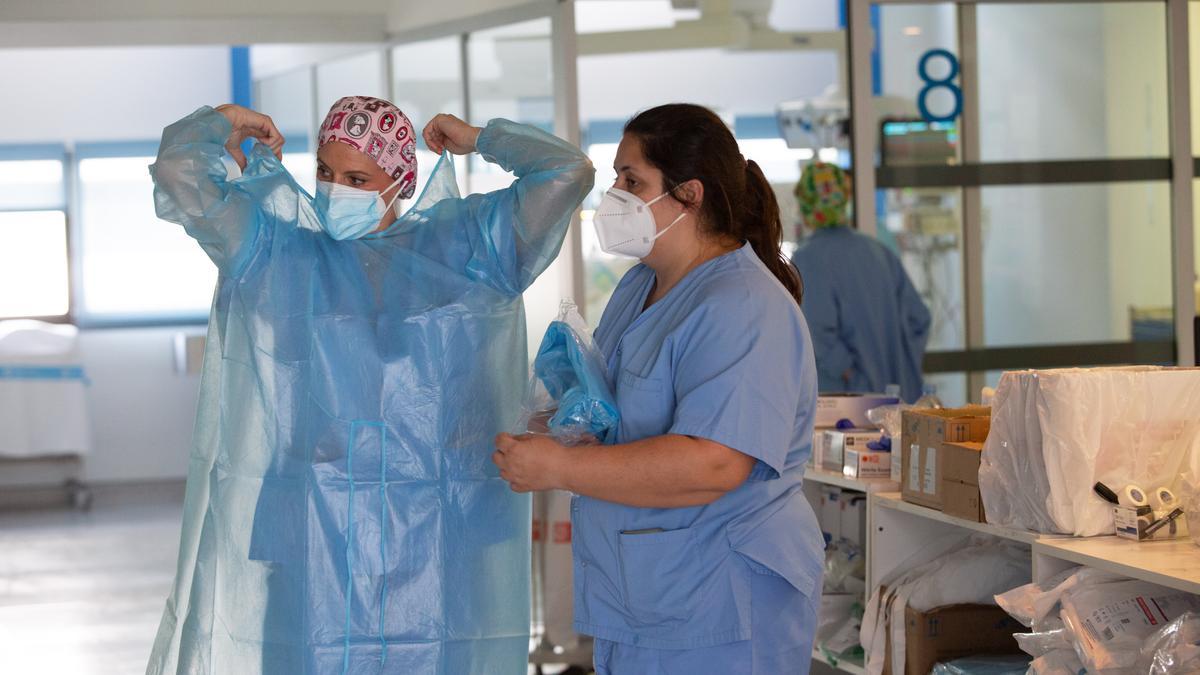 Una profesional sanitaria de la UCI del hospital Can Misses se pone el equipamiento de protección.
